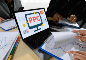 Laptop displaying "PPC" on screen, surrounded by hands reviewing financial charts and documents, illustrating digital marketing strategies and PPC analysis.